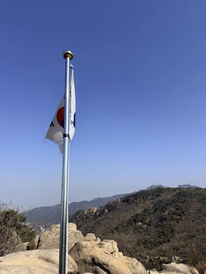 South Korean flag flying at Hoamsan Mountain summit with forested peaks