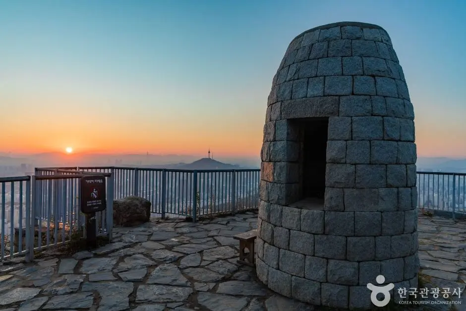 Stone tower structure at Ansan summit during sunrise with city view