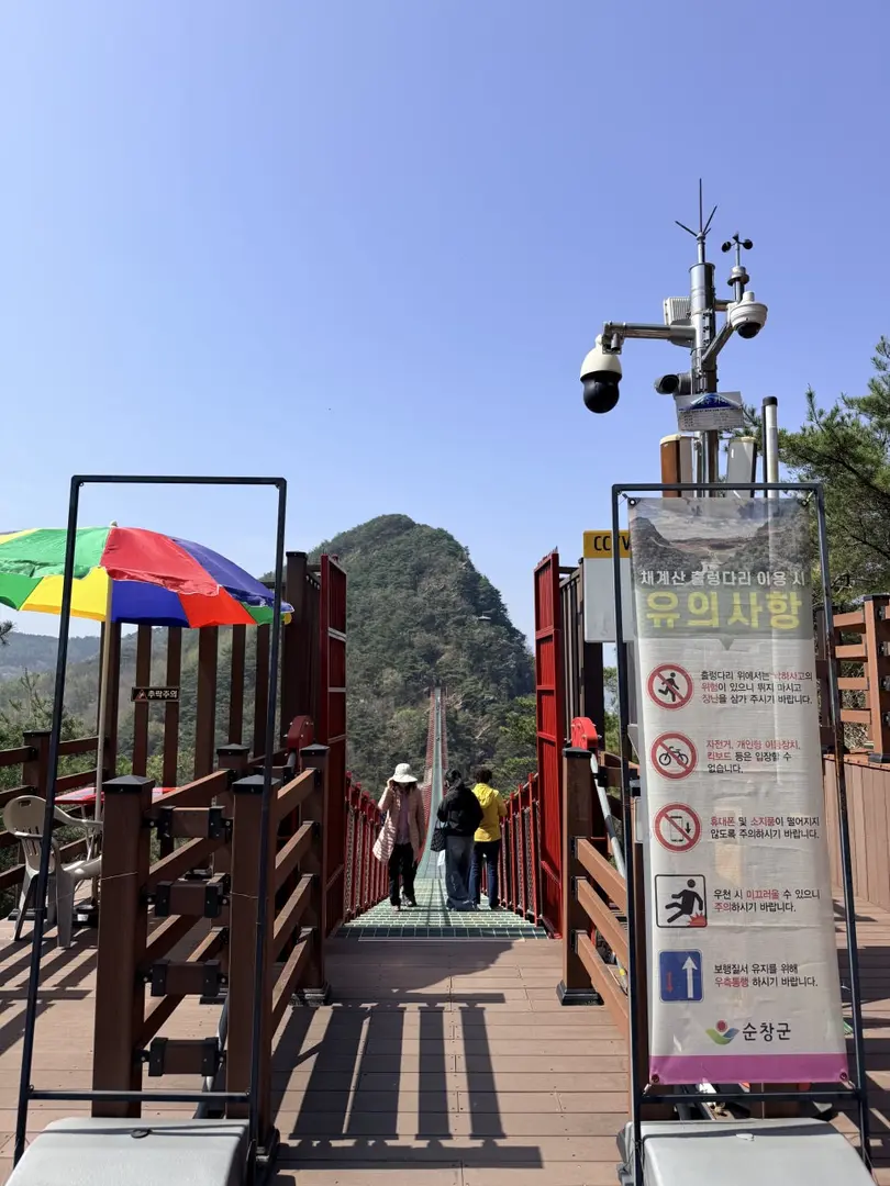 Red gates and colorful umbrella marking suspension bridge trail entrance
