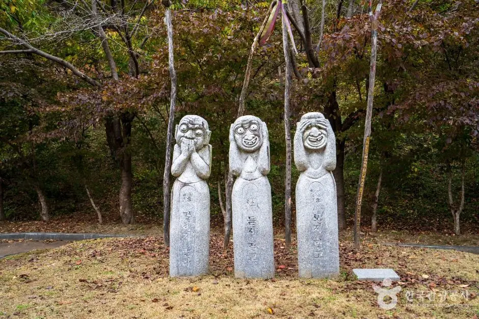 Three smiling stone jangseung statues in Chilgapsan Jangseung Park