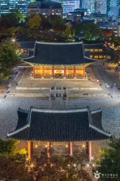 Aerial view of Deoksugung Palace illuminated at dusk with surrounding Seoul cityscape