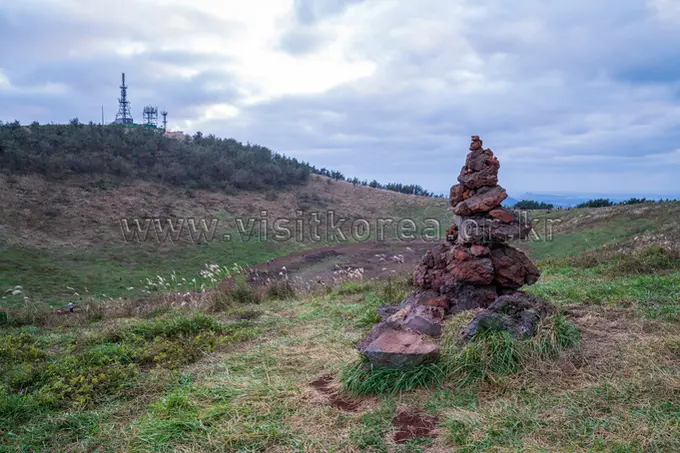Stacked red rock cairn on Geum Oreum hiking trail Jeju