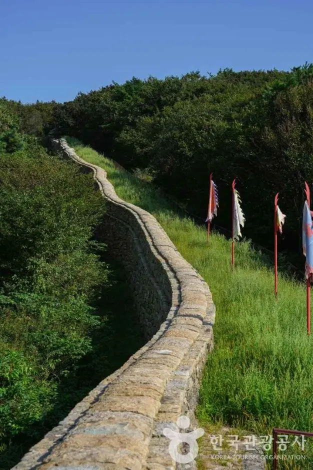 Ancient stone fortress wall along Geumjeongsan hiking trail with flags