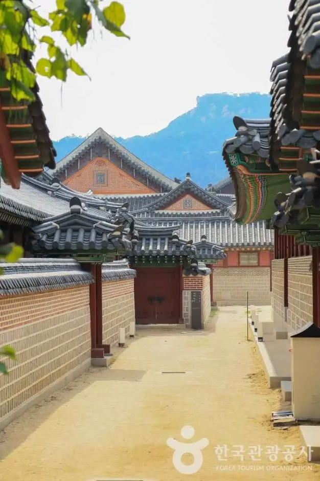 Traditional Korean palace courtyard with wooden buildings and mountains