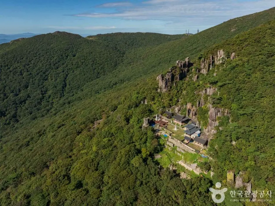 Gyubeongam temple set on rocky cliffs surrounded by lush green forest