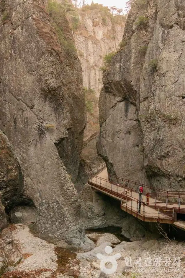 Wooden boardwalk suspended through narrow rocky gorge at Juwangsan National Park