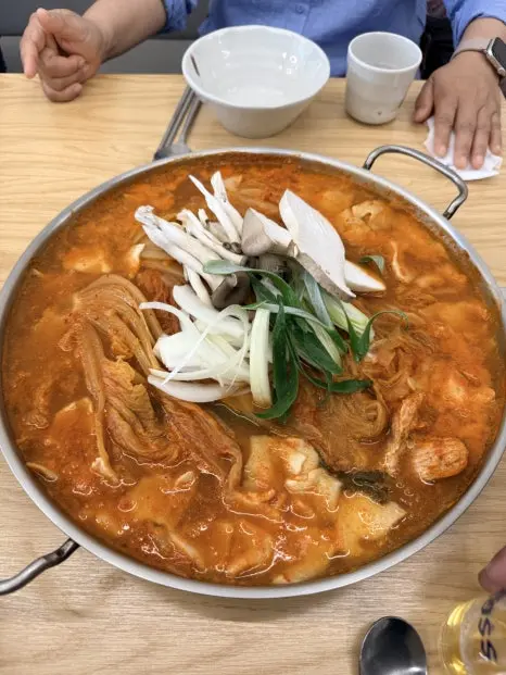 Mugeunji galbi-jjigae stew in large metal pot with sliced scallions and radish on top