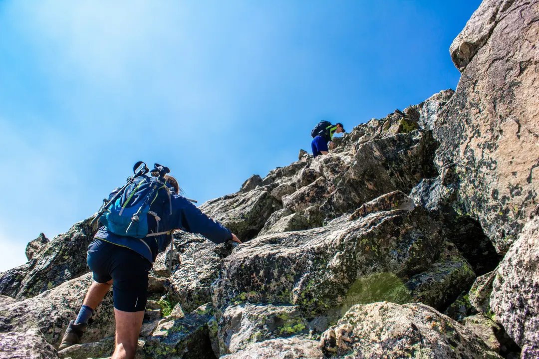 Hiker rock climbing on steep granite cliff face Dobongsan