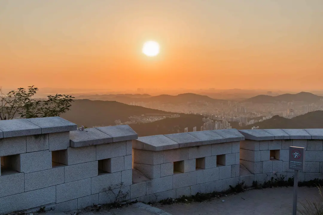 Seoul fortress walls at sunset with city skyline and mountains