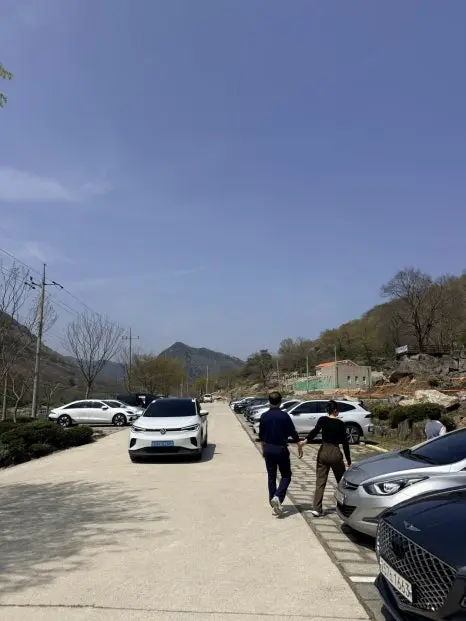 Parking lot at Yonggwolsan Sky Trail with multiple vehicles and hikers