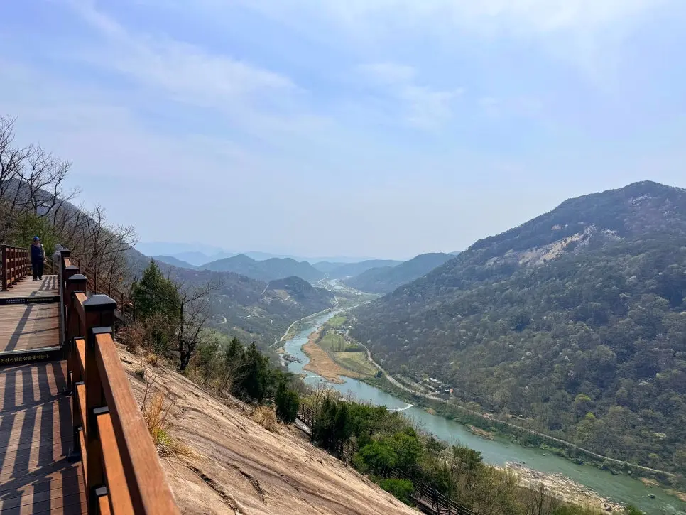 Sweeping view of turquoise Seomjingang River winding through forested valley from elevated boardwalk