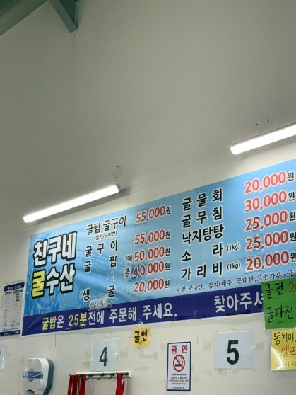 Menu board at Chinguné Gul Susan listing steamed oysters 굴찜(대) at 50,000원, raw oysters at 20,000원, octopus hotpot 낙지탕탕이 at 25,000원, and scallops 가리비 per kilo at 20,000원, among other shellfish dishes