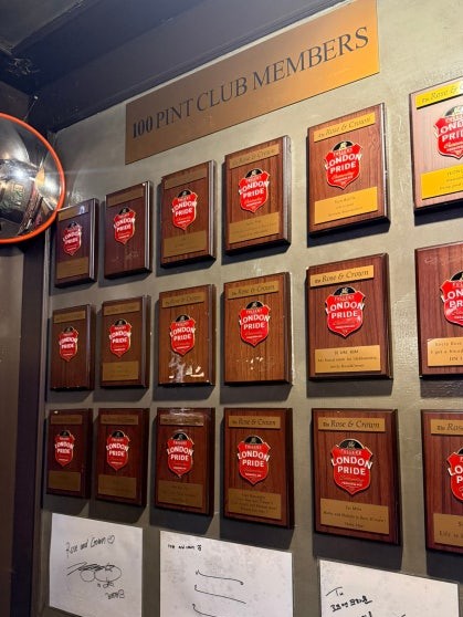 100 Pint Club Members wall at Rose & Crown with London Pride plaques, celebrity autographs, and handwritten notes in Korean and English