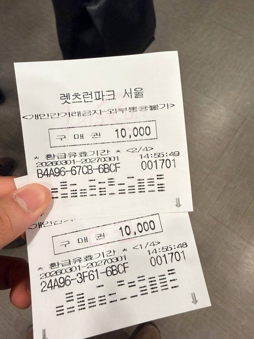 Two Let's Run Park Seoul betting vouchers each showing 10,000 won face value held in hand, printed with alphanumeric codes and dates