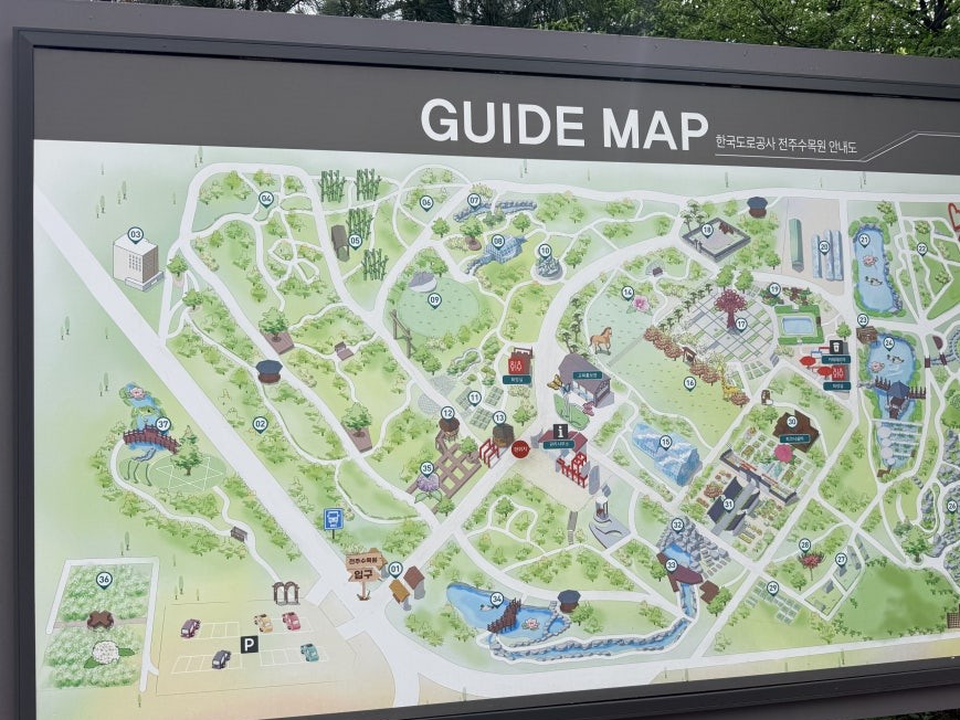 Large outdoor guide map board for Jeonju Arboretum mounted on a dark gray metal frame, showing an illustrated aerial layout with multiple numbered garden sections, parking area at lower left, and a Korean legend column on the right